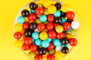 Colorful dragee candies close up on yellow background