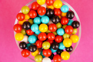 Multicolored round candies close up over fuchsia