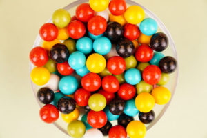 Multicolored round candies close up over light green